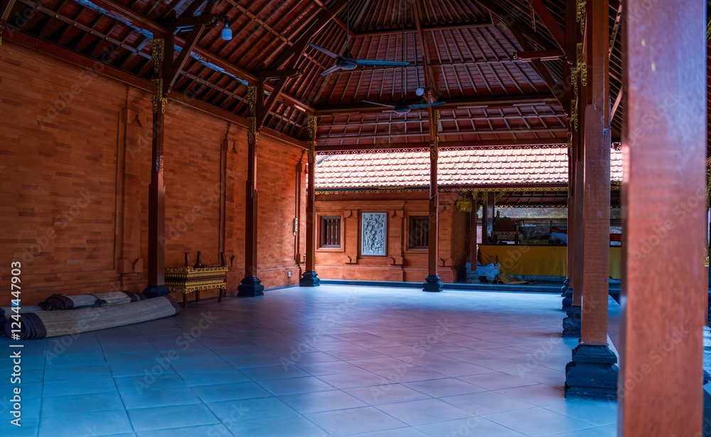 View of a traditional open pavilion featuring wooden beams and tiled roofs in Bali, Indonesia. The serene interior highlights intricate designs and cultural details, emphasizing peaceful