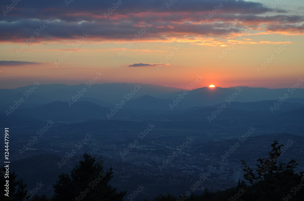 Fototapeta premium sunset over the city behind the mountains 