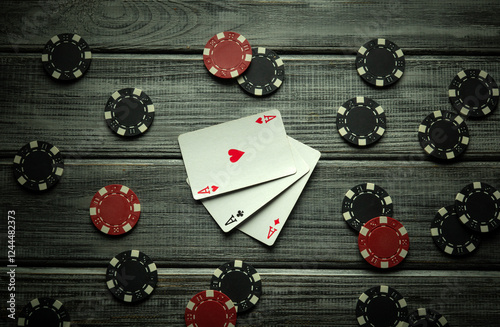 Obraz na plátně On a rustic wooden table, playing cards with a combination of three of a kind or set lie and black with red poker chips are displayed