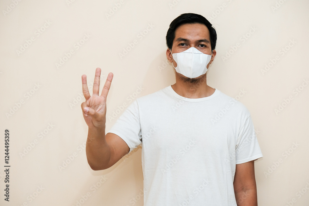 Southeast Asian man wearing hygienic mask with giving number 12345 by hand gesture isolated over white background. Healthcare medical concept Southeast Asian man wearing hygienic mask with giving number 12345 by hand gesture isolated over white background. Healthcare medical concept