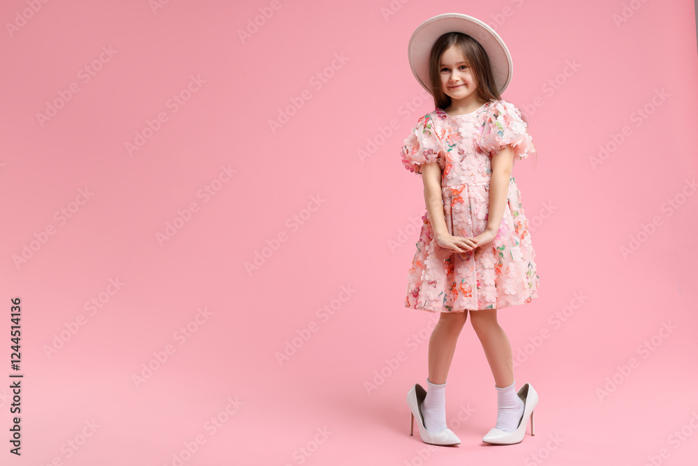 Stylish little girl wearing oversized high heeled shoes on pink background, space for text Stylish little girl wearing oversized high heeled shoes on pink background, space for text