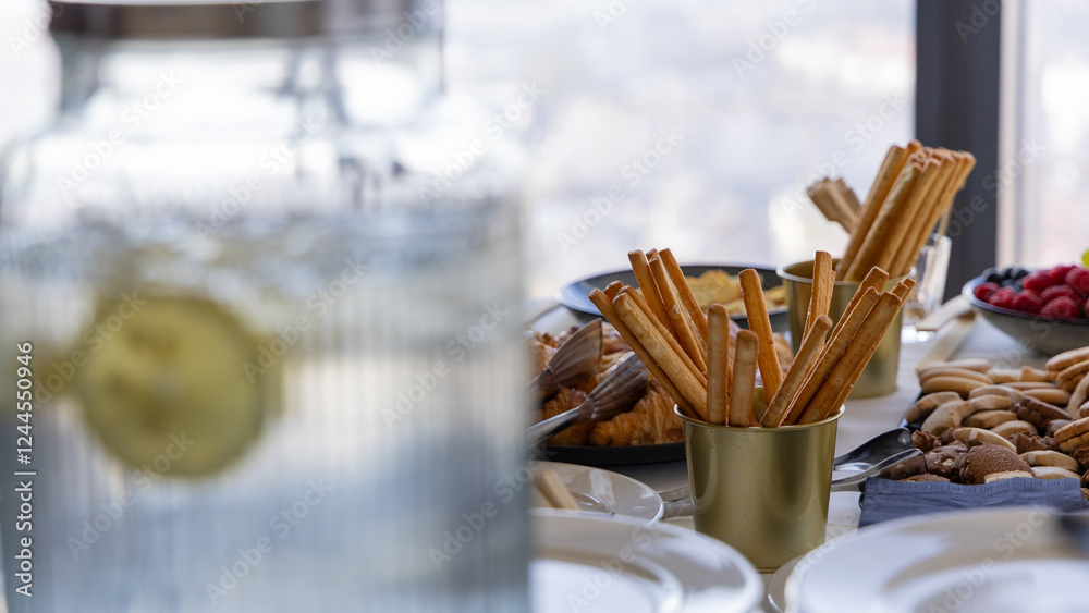 Different finger food, cookies and sesame sticks on a white table on a gala event or banquet. Lemonade jar in the foreground.