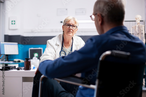 Foto Retired male patient in wheelchair provides health updates to his senior female physician at clinic