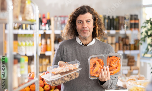 Adult man buyer chooses king prawns or purple dye murex (Bolinus brandaris) in grocery store photo
