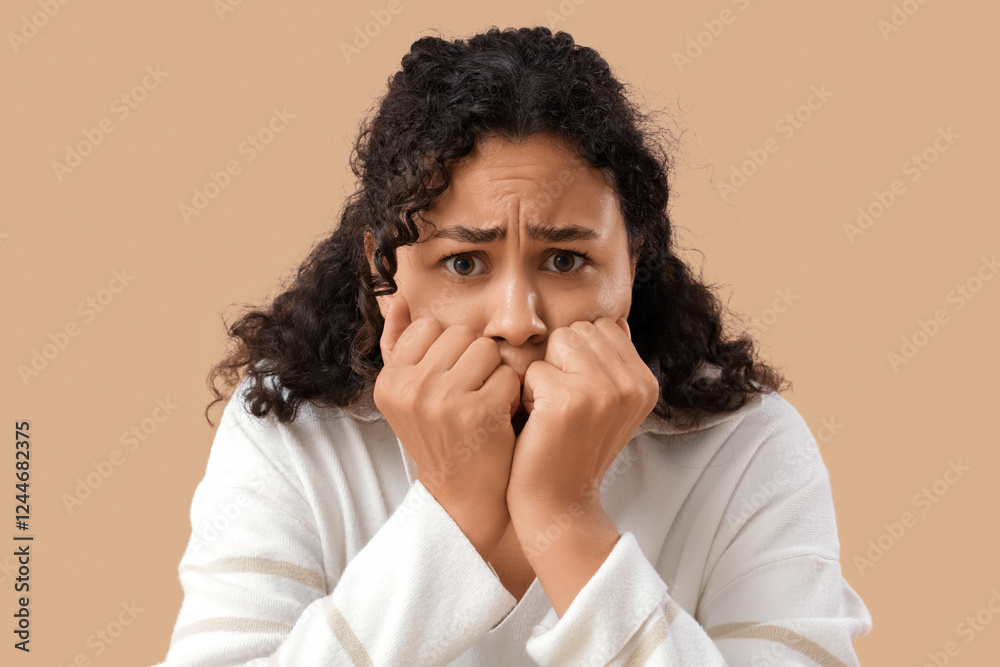 Young African-American woman having panic attack on beige background
