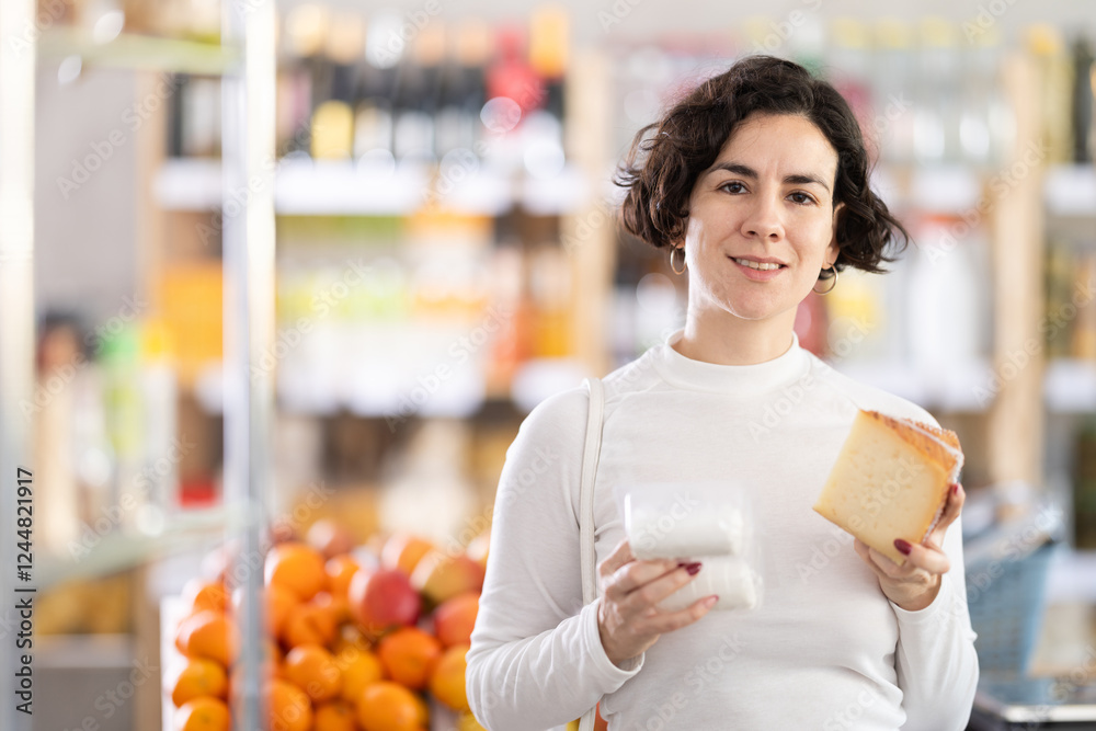 Adult woman buyer chooses fresh cheese in grocery store Adult woman buyer chooses fresh cheese in grocery store