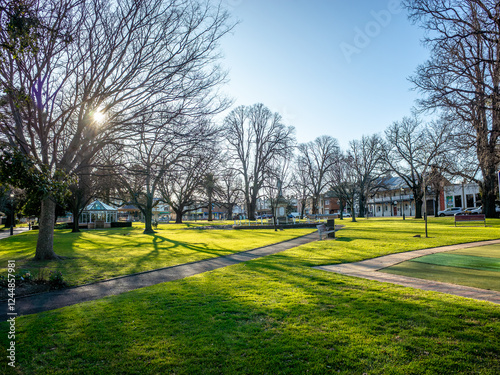 The historic Belmore Park features expansive green lawns bathed in late afternoon sunlight, creating a picturesque small regional town atmosphere at Goulburn, NSW Australia photo