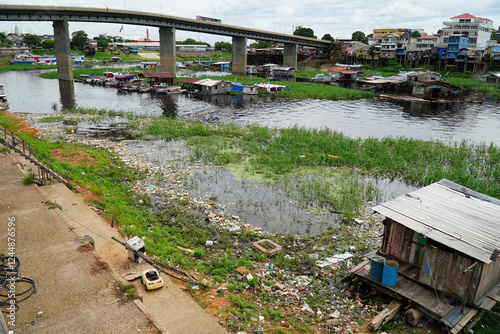 Plastic waste pollution in the Rio Negro river in Manaus, Brazil. Garbage on the river bank between boats, ships and houseboats. Lourenco da Silva Braga Street in downtown of the Amazon capital.