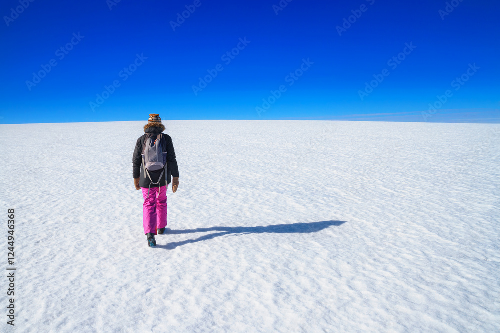 Arctic winter landscape - view of a snowy desert field with a walking man in the rays of the winter sun