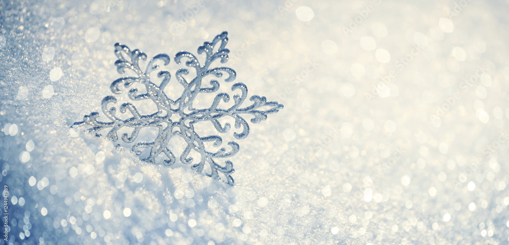 Christmas winter background, banner - view of a decorative snowflake on snow sparkling in the rays of the sun, copy space for text