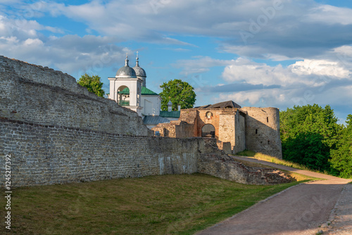 View of the wall of the Izborsk fortress, the Nikolsky Gate and St. Nicholas (Nikolsky) Cathedral (XIV-XVII century) on a sunny summer day, Izborsk, Pskov region, Russia photo