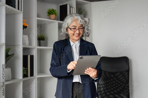 Senior female business executive using a tablet and smiling in a modern office, showcasing her expertise photo