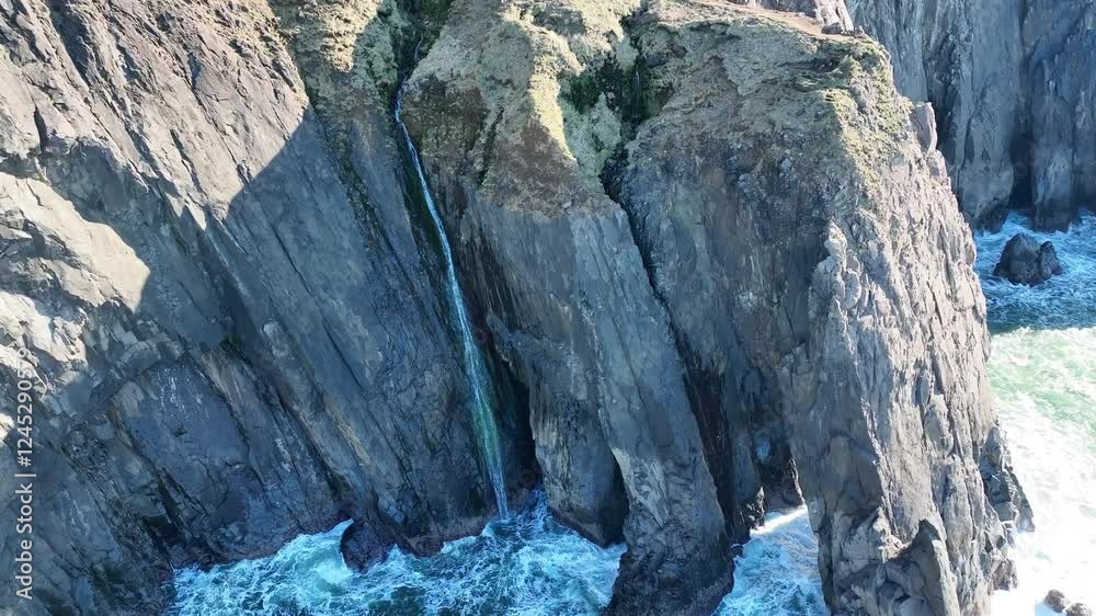 A narrow waterfall flows off a cliff into the ocean along the scenic coastline of northern Oregon. This beautiful area is accessible via highway 101 which runs along the entire west coast. A narrow waterfall flows off a cliff into the ocean along the scenic coastline of northern Oregon. This beautiful area is accessible via highway 101 which runs along the entire west coast.