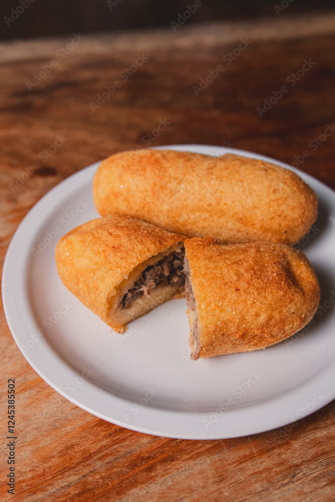 A minced view of a cassava bomb with meat inside on a wooden table. A minced view of a cassava bomb with meat inside on a wooden table.