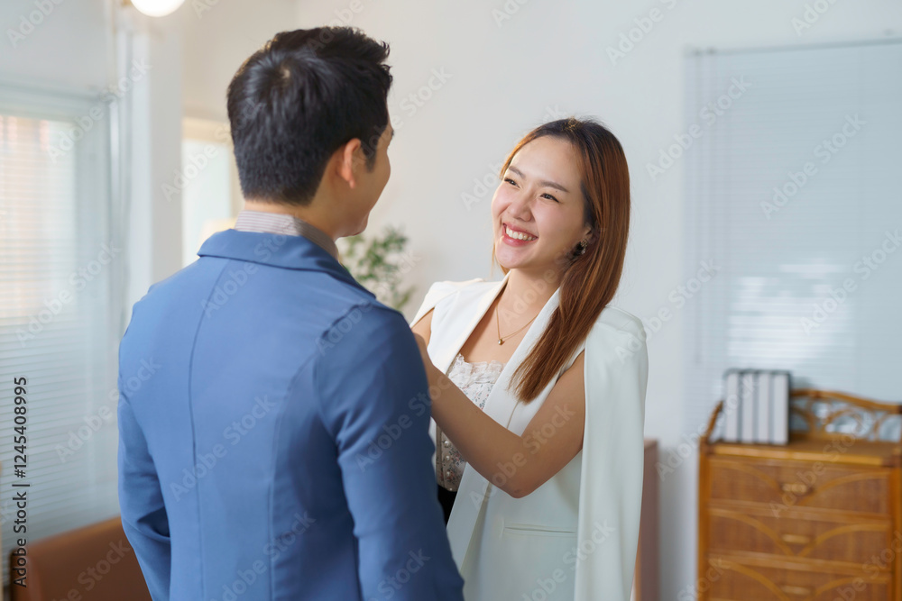 Asian businesswoman adjusting businessman suit in office Asian businesswoman adjusting businessman suit in office