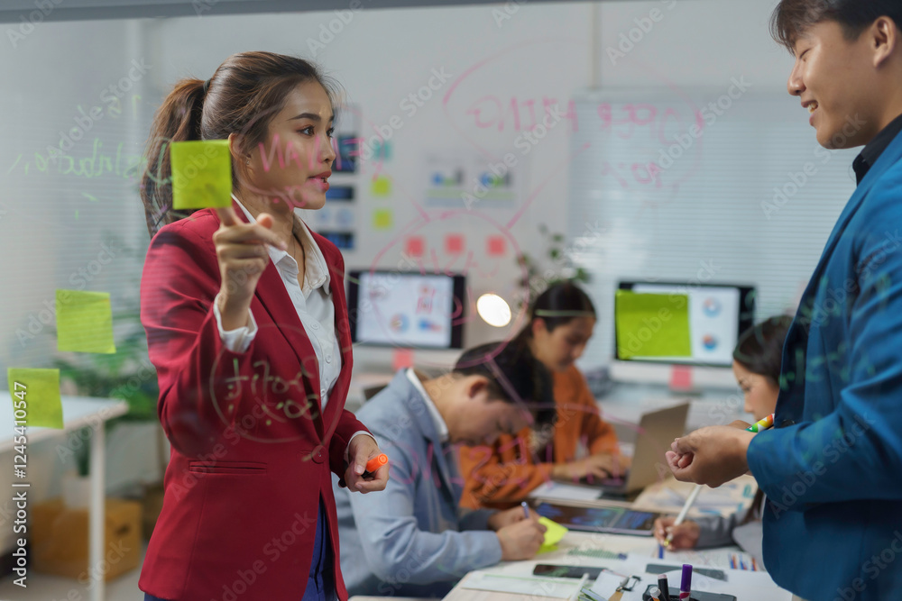 Asian businesspeople brainstorming and working together using sticky notes and glass board in modern office Asian businesspeople brainstorming and working together using sticky notes and glass board in modern office