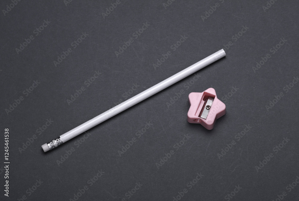 White sharpened pencil with sharpener on dark gray background White sharpened pencil with sharpener on dark gray background