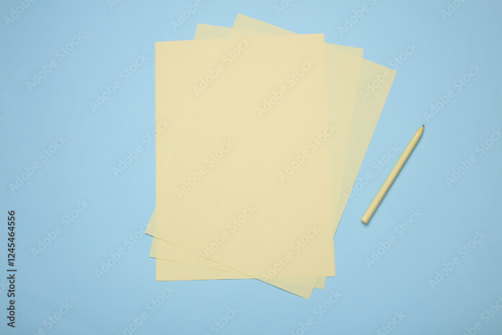 Fototapeta premium Yellow sheets of paper with pencil on blue background