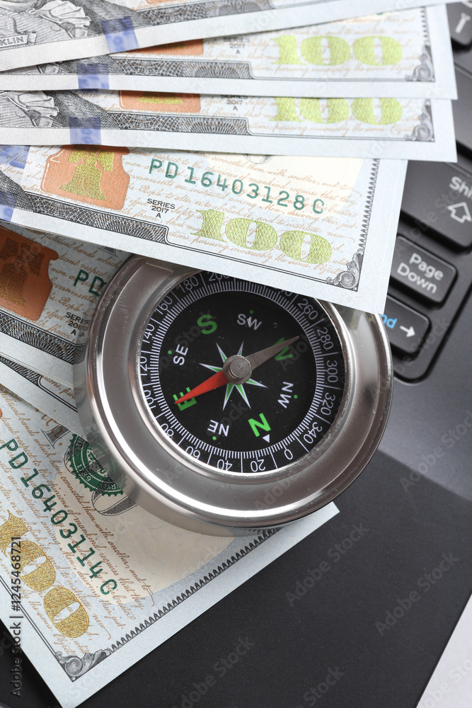 Laptop with dollar bills and compass on white background. Business concept Laptop with dollar bills and compass on white background. Business concept