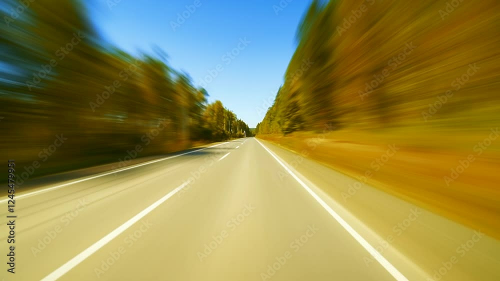A car racing through a scenic autumn forest on a county road. A car racing through a scenic autumn forest on a county road.