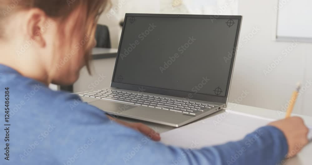 Using laptop and writing in notebook, student studying in school classroom, copy space Using laptop and writing in notebook, student studying in school classroom, copy space
