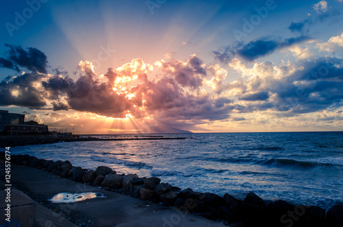 sunset behind clouds,  over the sea