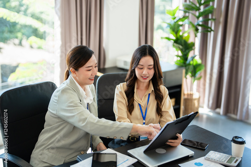 Foto Female senior and junior managers sitting at desk working together in a business
