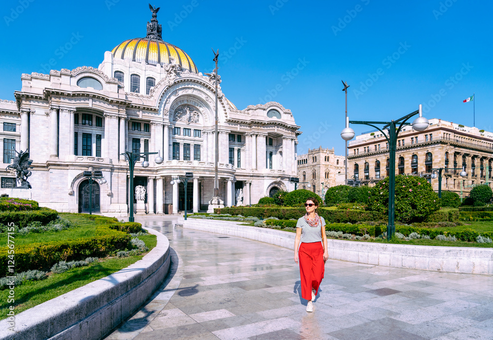 A woman walking near the iconic Palacio de Bellas Artes in Mexico City, with its stunning white marble facade and golden dome under a clear blue sky