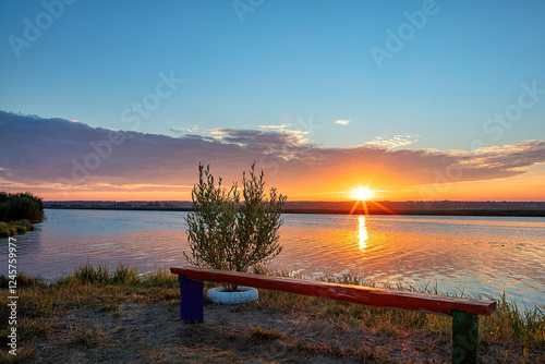 Obraz na płótnie Majestic sunset over tranquil waters with a colorful bench in a serene landscape w salonie