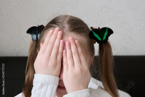 A little girl holds a tropical neon butterfly on her arm. The concept of creativity, the exploration of the living world. The life of tropical butterflies at home. Farm butterfly at home
 photo