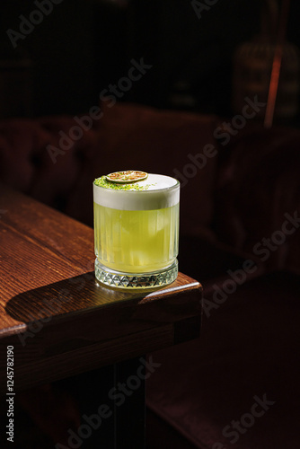 Unique green cocktail served in a stylish glass on wooden table at a cozy bar in the evening