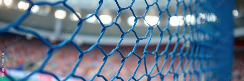 Naklejka premium Close-up view of blue goal netting at a vibrant sports stadium during a lively soccer match in an afternoon setting