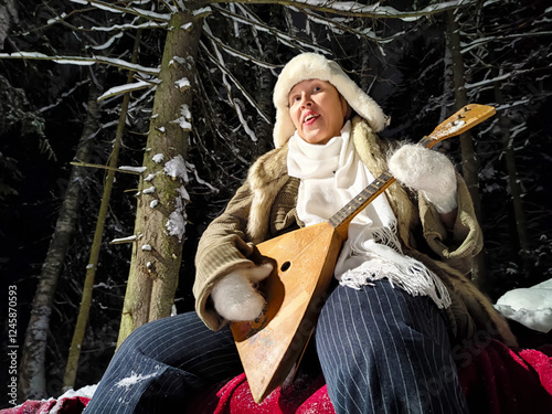 Fotografie Funny middle-aged woman enjoying a night walk in the snowy woods while playing a