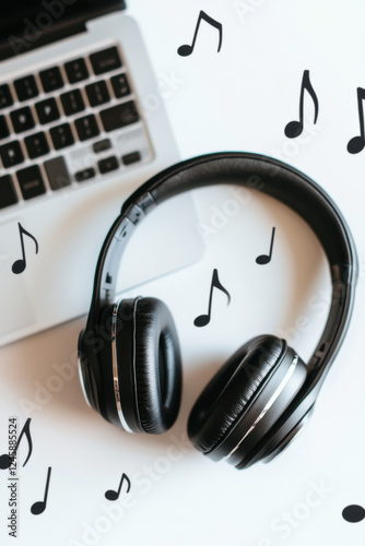 A pair of headphones dancing to music notes floating from a nearby laptop