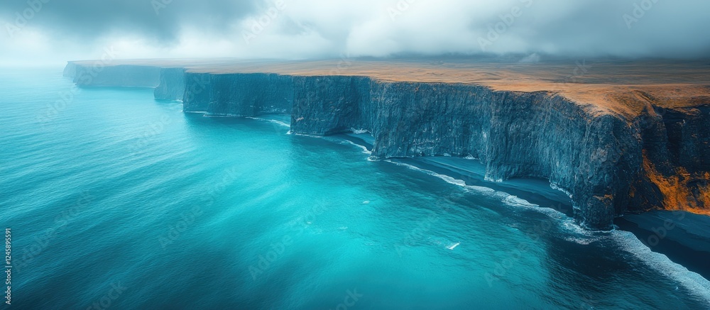 Fototapeta premium Stunning aerial view of the dramatic southern coastline of Iceland showcasing turquoise waters and rugged cliffs under a moody sky