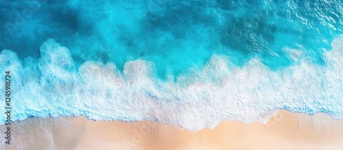 Aerial view of vibrant blue sea surface with gentle waves and sandy shore creating a serene coastal landscape background photo