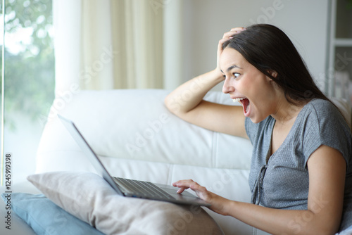Amazed woman checking good news on personal computer