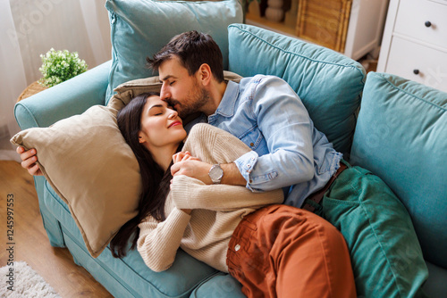 Fotografie Couple relaxing at home cuddling on living room couch
