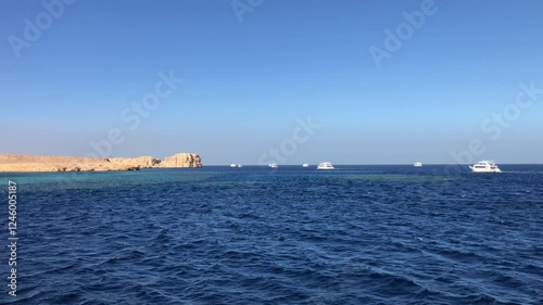 Many tourist yachts in the Red sea with desert mountains in the background. View from the Shark Observatory in Ras Mohammed National Park . Scuba Diving excursion