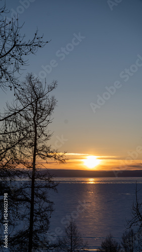 Shimmering Sunset Reflections on Ice - A captivating view of the sun setting over the frozen Khovsgol lake, with shimmering light reflecting off the icy surface. photo