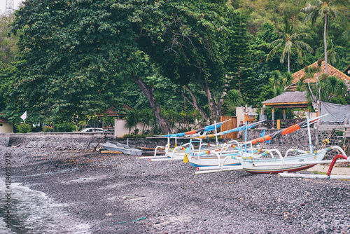 Tranquil seaside scene featuring traditional fishing boats on a pebbly shore beneath lush greenery, evoking peace and natural beauty..