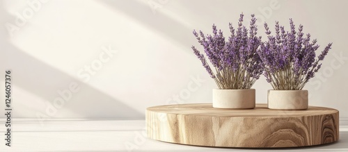 Wooden podium with light natural wood tone displaying two round white pots of dried lavender flowers in muted purple against a soft white backdrop photo