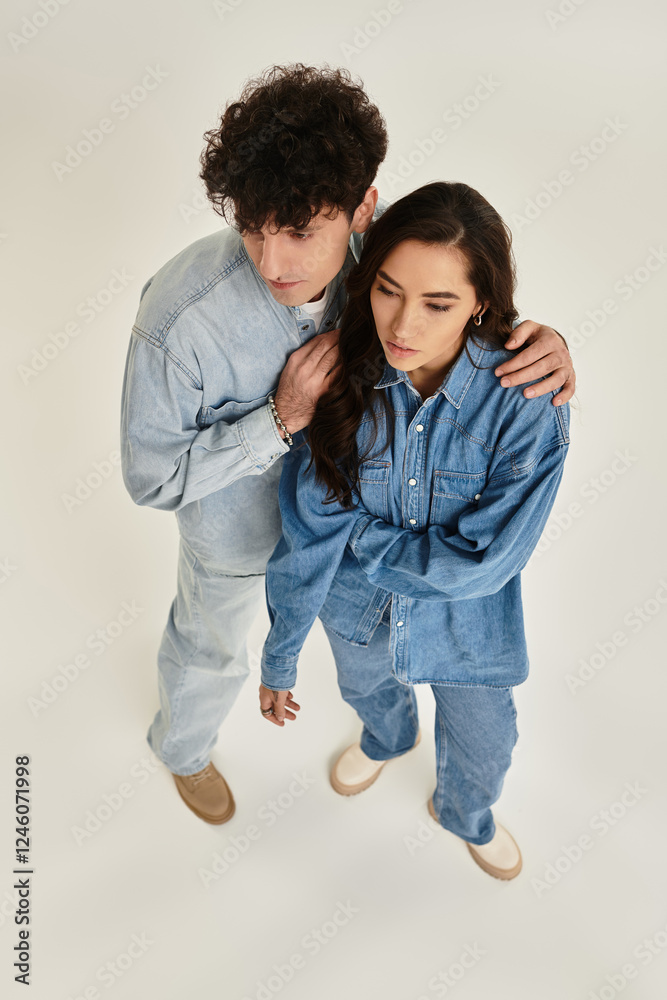 Stylish young couple showcases trendy denim fashion in modern studio setting Stylish young couple showcases trendy denim fashion in modern studio setting