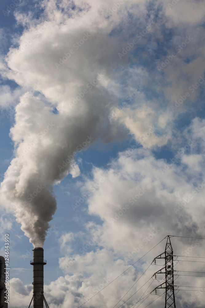 Chimney with smoke from a wood processing industry and an electric power pole. Electricity with blue sky and white clouds. Pollution Chimney with smoke from a wood processing industry and an electric power pole. Electricity with blue sky and white clouds. Pollution