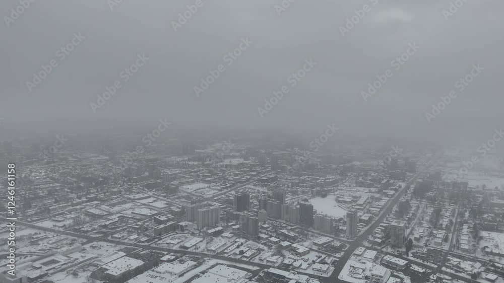 Drone footage of ice-covered city under snowfall and dense fog during a deep winter season