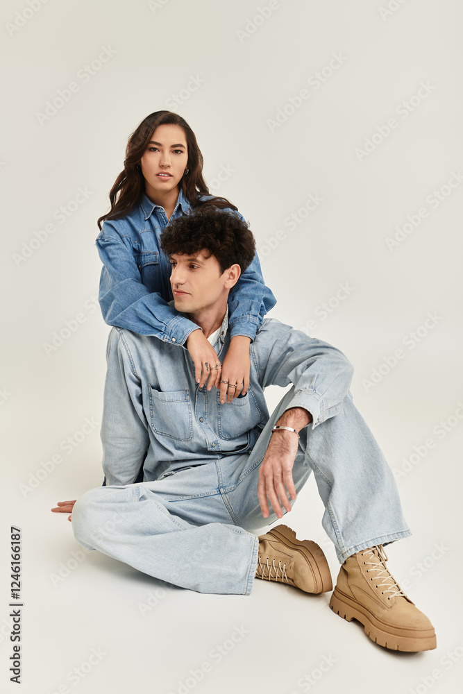 Stylish young couple showcases contemporary denim fashion in a minimalist setting