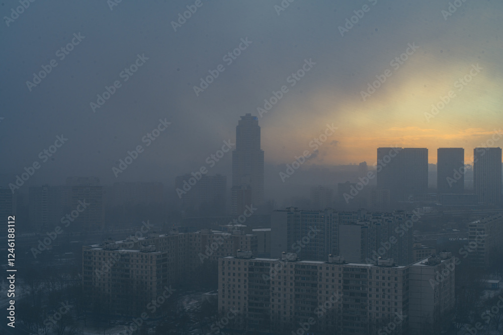 Fototapeta premium A snowstorm covers the big city, a gloomy sky with glimpses of the sun. Aerial shooting. Space for text.