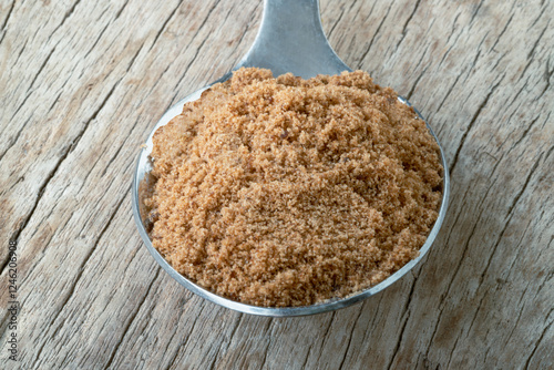 Obraz na płótnie Powdered brown sugar or Brown granulated sugar in Silver spoon isolated on Old rustic wooden table. use it as your Space for text, Design, Wallpaper and Poster, Selective focus. w salonie