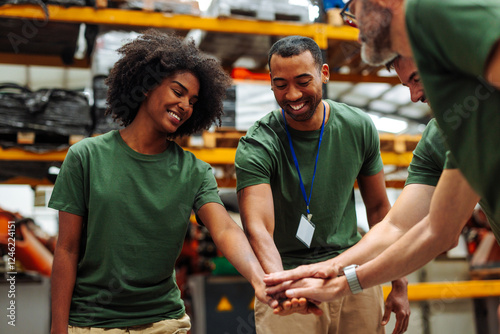 Warehouse workers joining hands for teamwork and collaboration