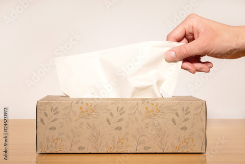 Close-up of a hand taking a tissue from a box.